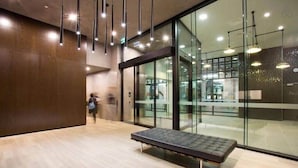 A modern interior with a bench, glass walls, and hanging lights. - Comfy 2BR Apt Near Southern Cross With City Views (Melbourne)