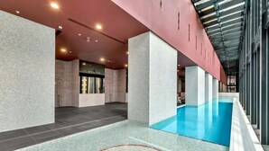 Une piscine intérieure moderne, dotée d’un système de filtration à eau claire, entourée d’un sol et de murs carrelés à la finition texturée.