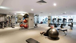 Un gimnasio con diverso equipo de ejercicio, como cintas de correr, bicicletas estáticas y pesas sueltas.