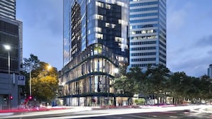 A modern building with a curved facade, large windows, and a parking sign. - Lovely 3BR Apt With Panoramic Views, Free Parking (Melbourne)