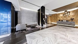 A modern lobby with a reception desk, seating area, and a large marble floor.