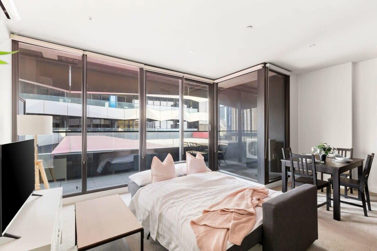 Una habitación de hotel moderna con una cama grande, un escritorio y un comedor.