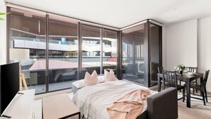 A modern hotel room with a large bed, a desk, and a dining area.