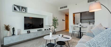 Una sala de estar moderna con una televisión de pantalla plana, una mesa de comedor redonda y un sofá.