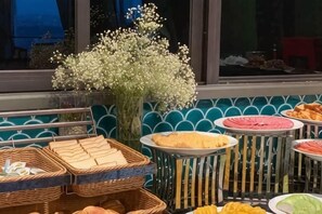 A buffet with various food items and a decorative flower arrangement. - MADELISE HOTEL&APARTMENT (Haiphong)
