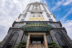 A hotel entrance with a clock, a sign reading 'MADELISE HOTEL,' and a traditional architectural style. - MADELISE HOTEL&APARTMENT (Haiphong)