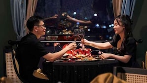 A couple toasting at a table with a view of a cityscape. - MADELISE HOTEL&APARTMENT (Haiphong)
