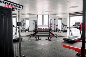 A gym with cardio equipment, weightlifting stations, and mirrors on the walls. - MADELISE HOTEL&APARTMENT (Haiphong)