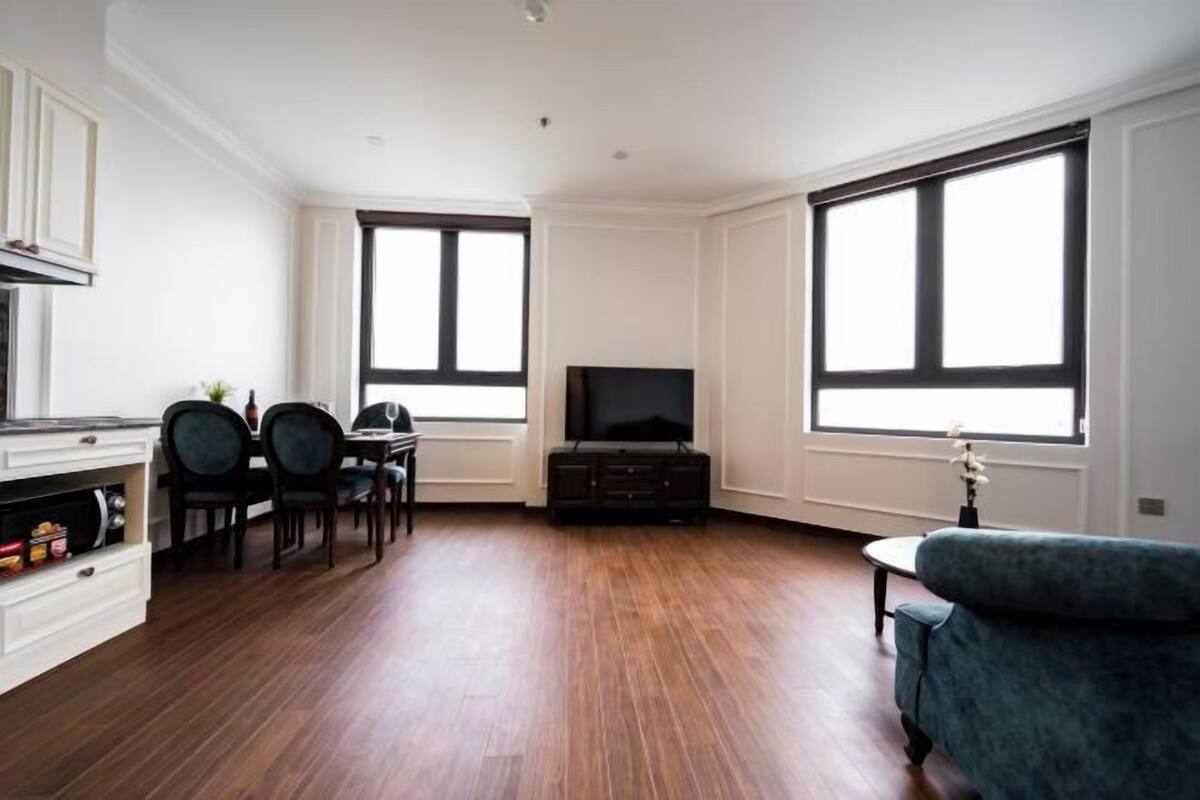 A spacious living area with a flat-screen TV, a dining table with chairs, and a sofa.