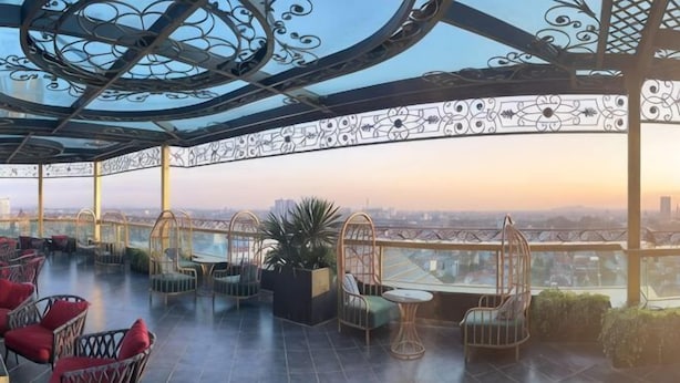 A rooftop terrace with outdoor seating, a glass ceiling, and a city view. - MADELISE HOTEL&APARTMENT (Haiphong)