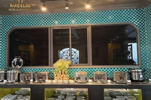 A hotel bar area with a large window, a decorative plant, and various kitchen appliances. - MADELISE HOTEL&APARTMENT (Haiphong)
