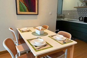 A dining table set with white plates, cutlery, and a tissue box, surrounded by wicker chairs. - MH Platinum 2 Blissful Fully Aircon Suite (Kuala Lumpur)