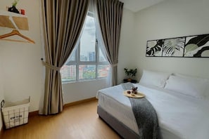 Un dormitorio con cama, cortinas, una ventana, una planta y obras de arte en la pared.