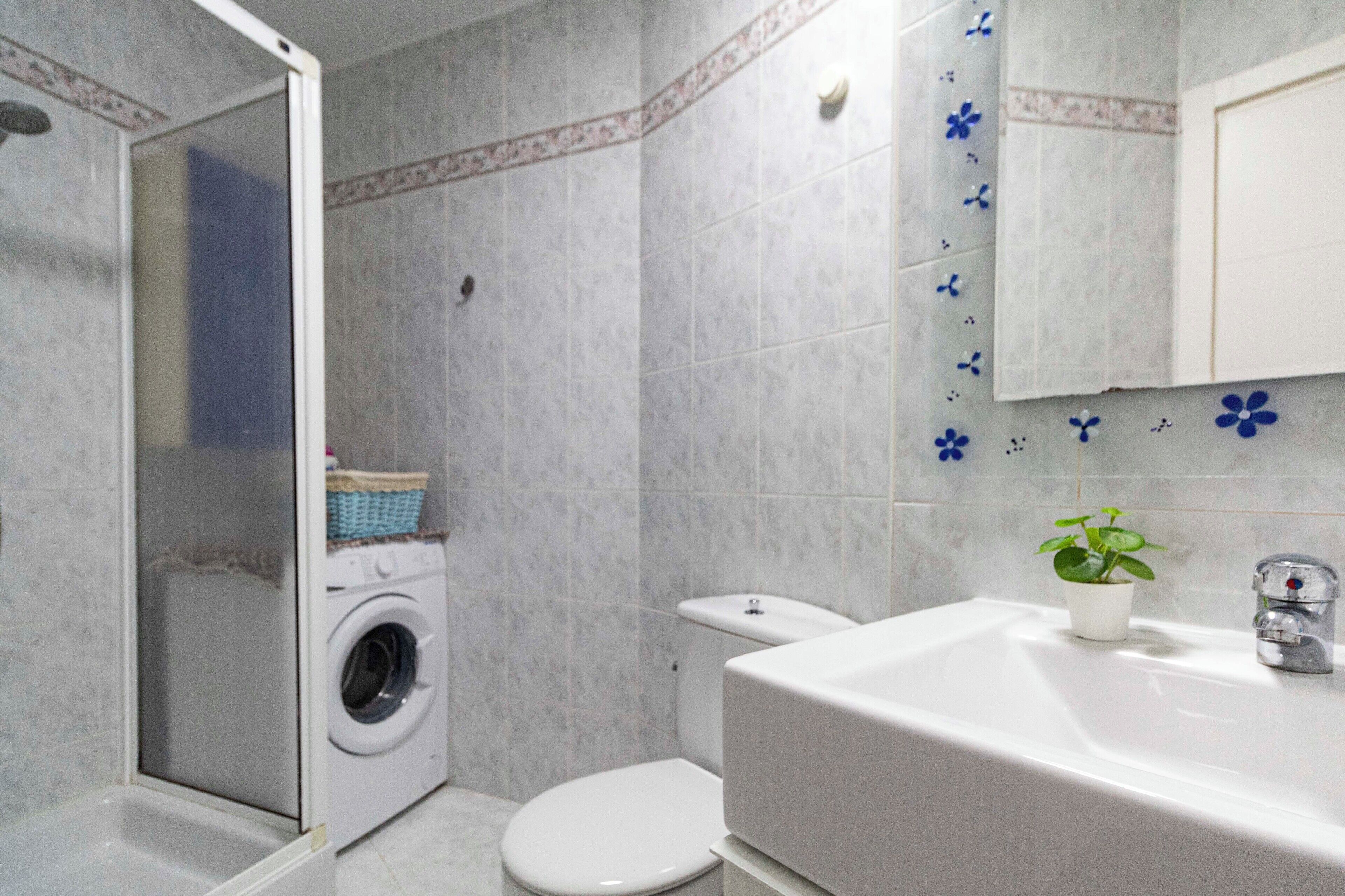 Een badkamer met een wasmachine, toilet en bad.