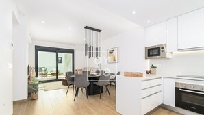 A modern kitchen with white cabinetry, a built-in microwave, and a stainless steel oven. - Nalia Horizon Penthouse, Outdoor living with solarium, BBQ, pool, hot tub - by OYOOSTAYS (Torrevieja)