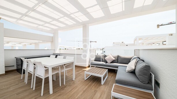 A modern, open-plan living space with a dining area, sofa, and wooden flooring. - Nalia Horizon Penthouse, Outdoor living with solarium, BBQ, pool, hot tub - by OYOOSTAYS (Torrevieja)