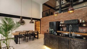 A modern kitchen with a brick wall, wooden dining table, and pendant lights. - Villa Koma by BaliSuperHost (Bali)