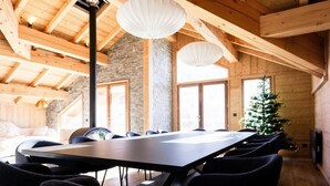 Ein Konferenzraum mit einem langen Tisch, Stühlen, Holzbalken, Steinwänden und einem Weihnachtsbaum.