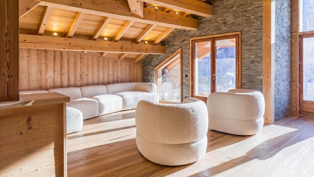 Ein gemütliches Zimmer mit Holzbalken, Steinwänden und großen Fenstern.