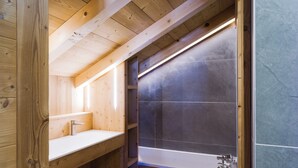 Ein Badezimmer einer Holzhütte mit einem Waschbecken, einer Duschkabine und einem Fenster.
