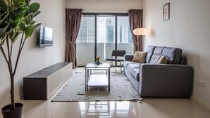 A modern living room with a sofa, a coffee table, and a TV on the wall. - A Lovely & Comfy Suite at Suasana Suites JB 11 (Johor Bahru)