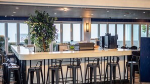 A bar area with a long counter, multiple stools, a coffee machine, and a large potted plant. - A Lovely & Comfy Suite at Suasana Suites JB 11 (Johor Bahru)