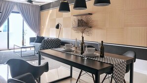 A modern dining area with a long table, black chairs, and pendant lighting. - A Comfy & Stylish Suite at Suasana Suites JB 11 (Johor Bahru)