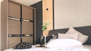A modern bedroom with a bed, a wardrobe, and a bedside table with a plant. - A Comfy & Stylish Suite at Suasana Suites JB 11 (Johor Bahru)