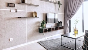A modern living room with a flat-screen TV, built-in shelves, and a dining area with a patterned rug. - A Comfy & Stylish Suite at Suasana Suites JB 11 (Johor Bahru)