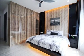 A modern bedroom with a bed, a ceiling fan, a cityscape artwork on the wall, and a wardrobe with a wooden finish. - A High-floor 2BR Suasana Suites, Near Ciq, JB (Johor Bahru)