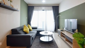 A modern living room with a sofa, coffee table, TV, and a plant. - Chic & Cozy Stay at Suasana Suites JB (Johor Bahru)