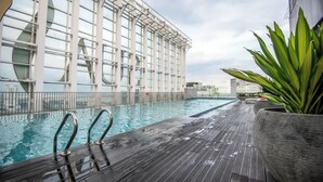 A rooftop pool with a wooden deck, surrounded by glass walls and a large window structure. - Chic & Cozy Stay at Suasana Suites JB (Johor Bahru)