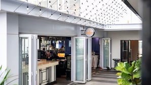 A modern hotel lobby with a glass partition, a reception desk, and a dining area. - Chic & Cozy Stay at Suasana Suites JB (Johor Bahru)