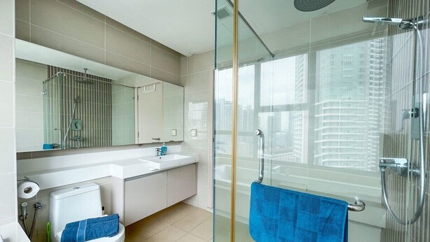 A modern bathroom with a glass-enclosed shower, a white toilet, a sink, and a large mirror. - Modern High Floor 3BR Apt Bathtub Bkt Bintang (Kuala Lumpur)