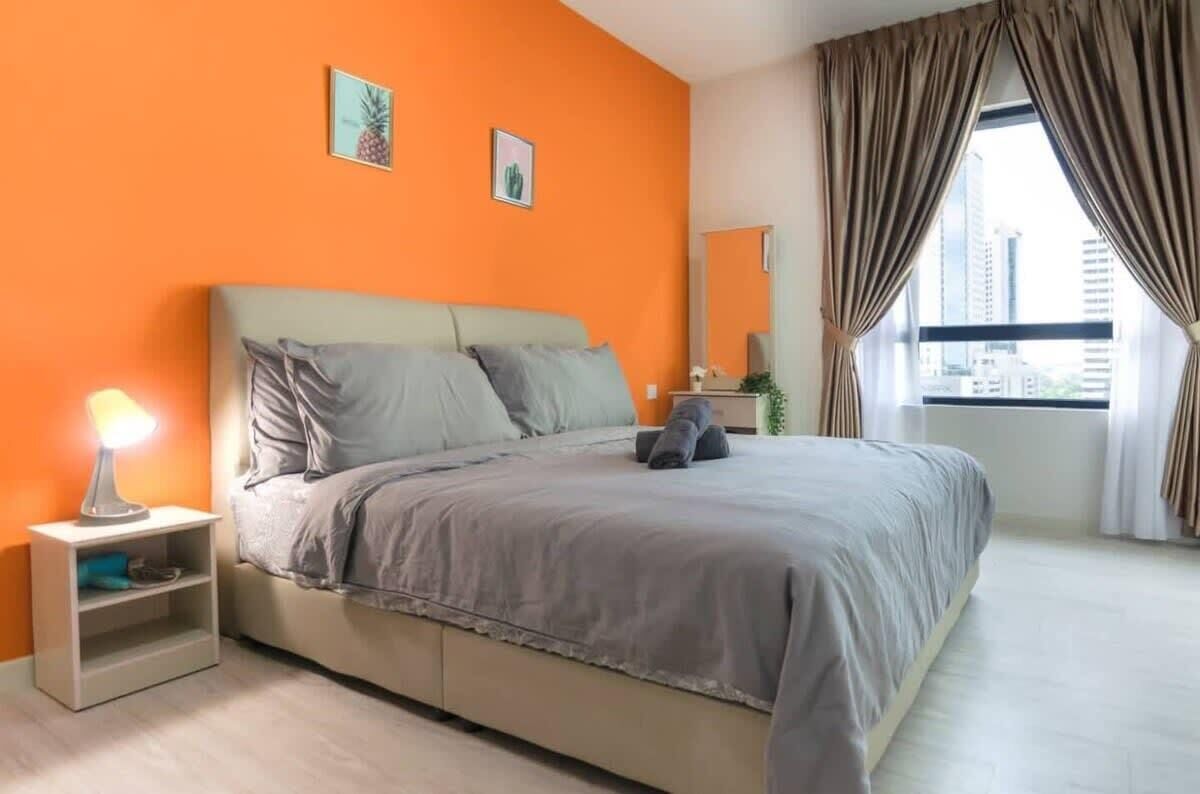 A bedroom with a bed, a nightstand, a lamp, and a window with curtains.