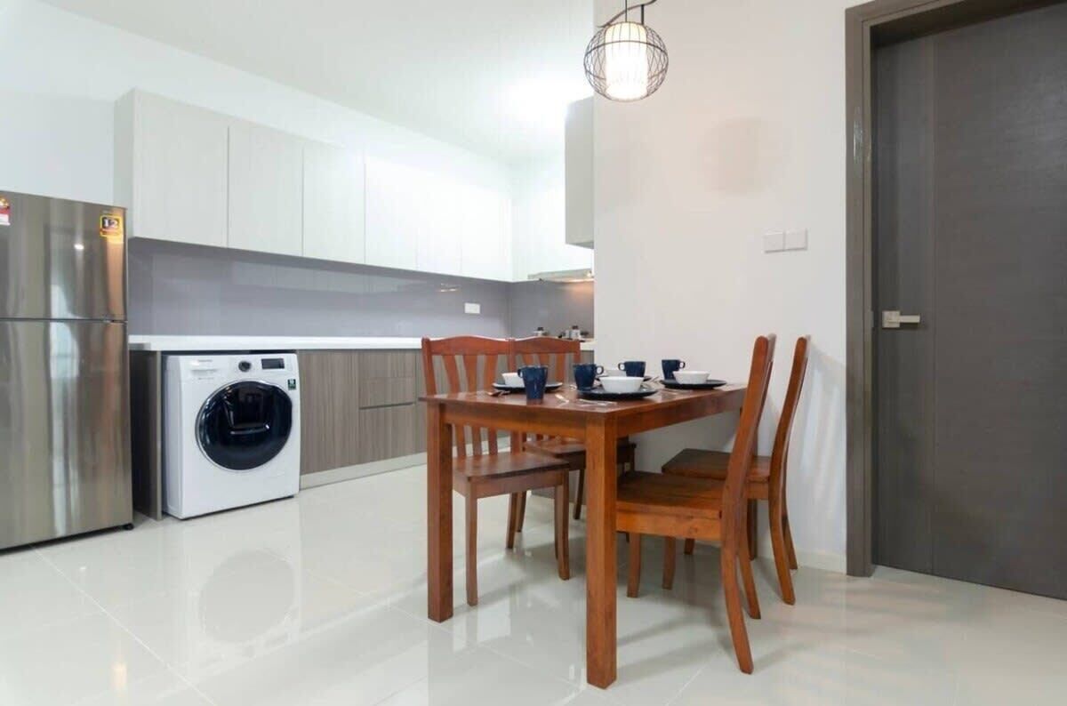 A modern kitchen with a built-in washing machine, a dining table with chairs, and a pendant light.
