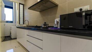 A modern kitchen with a black countertop, white cabinets, a stainless steel range hood, and a Samsung refrigerator.