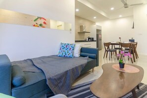 A modern living room with a sofa, a coffee table, and a dining area with chairs and a table. - 3BR D'pristine Suite Near Legoland, Stunning Views (Iskandar Puteri)