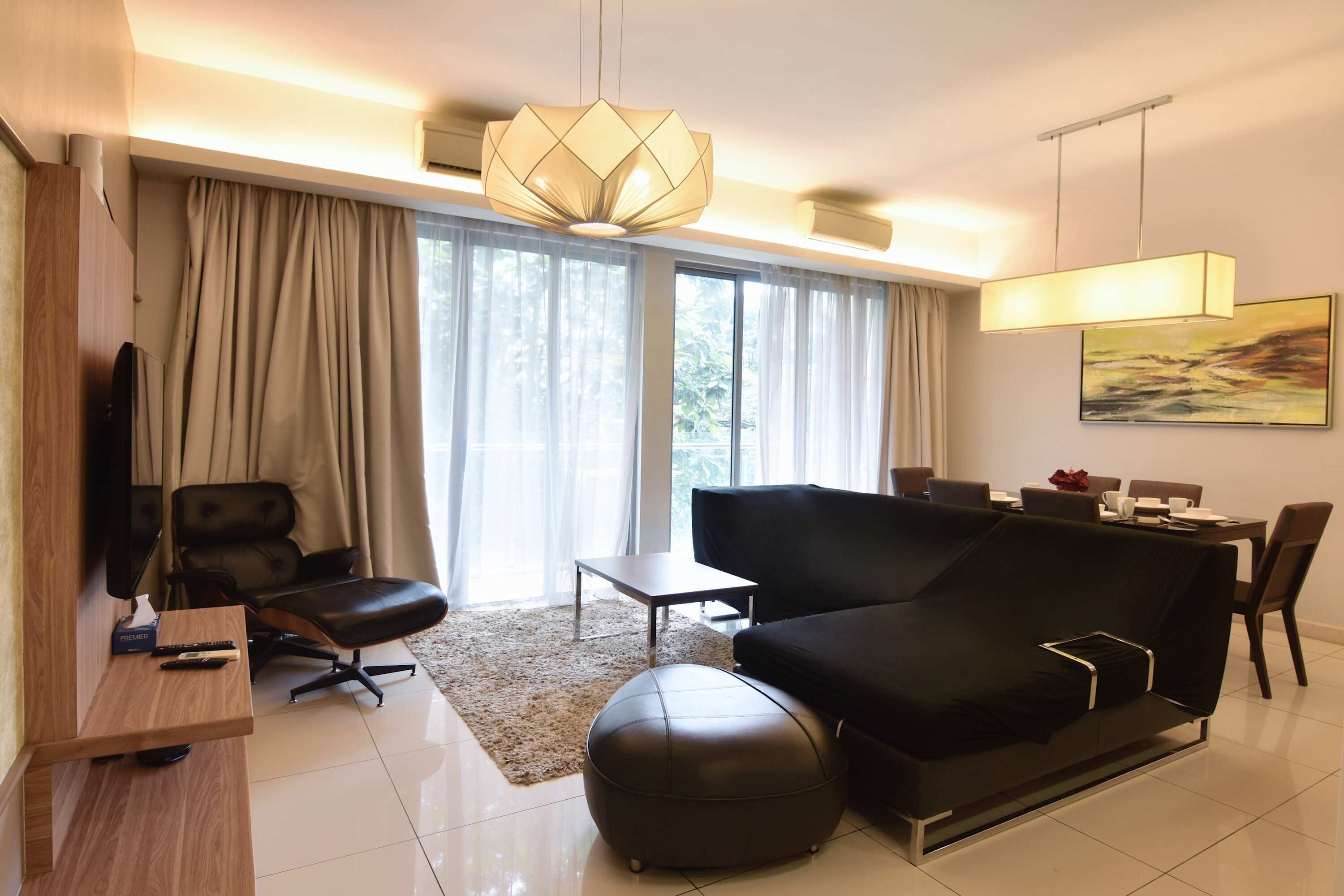 A modern living room with a black sofa, a coffee table, a TV, and a large window with curtains.