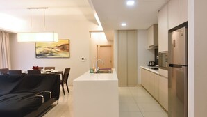A modern kitchen with a central island, stainless steel appliances, and a dining area with a sofa and table. - Pet Friendly, 3BR Apt KL, Bathtub & Parking (Kuala Lumpur)
