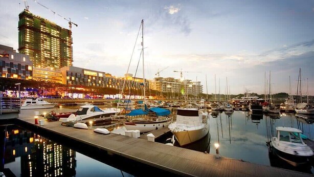 A marina with boats docked, a building under construction, and a calm waterfront. - A Stylish & Cozy Suite at Suasana JB 03 (Johor Bahru)