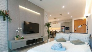 A modern hotel room with a large bed, a flat-screen TV mounted on the wall, a small kitchen area, and a dining table. - A Stylish & Cozy Suite at Suasana JB 03 (Johor Bahru)