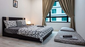 Une chambre moderne avec un grand lit, une table de chevet avec une lampe et une vue sur les immeubles à travers une fenêtre avec des rideaux.