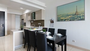 A modern kitchen with a dining area, a painting of a cityscape, and a black door. - A Stylish High Floor 3BR Apt at Bukit Bintang (Kuala Lumpur)