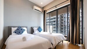 Une chambre d’hôtel avec deux lits, une grande fenêtre avec des rideaux et un climatiseur fixé au mur.
