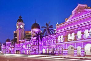 A historic building with multiple domes and arches, illuminated in purple.