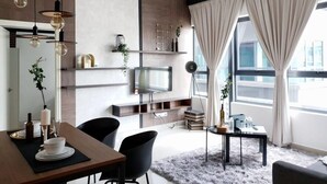 Un salon moderne comprenant un coin repas, un téléviseur fixé au mur et un ventilateur de plafond.
