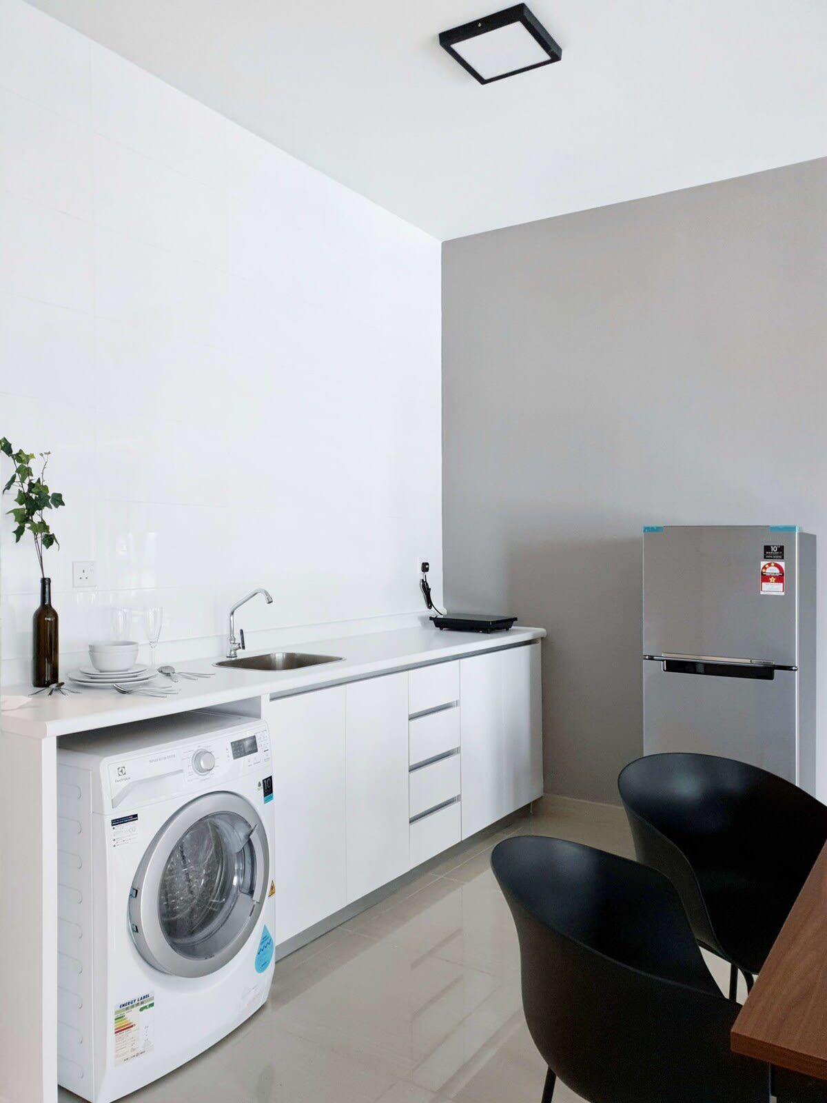 A modern kitchen with a built-in washer and dryer, a sink, and a refrigerator.