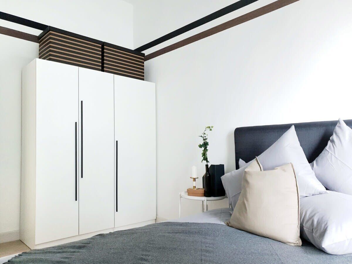 Ein Schlafzimmer mit Bett, Nachttisch, Kleiderschrank und einer Pflanze.