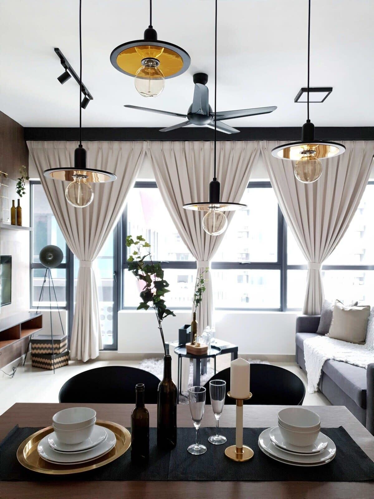 A modern dining area with a table set for two, a ceiling fan, and large windows with curtains.